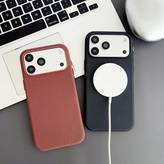 Two phone cases, one brown and one black with a MagSafe disc, on a desk with a laptop.