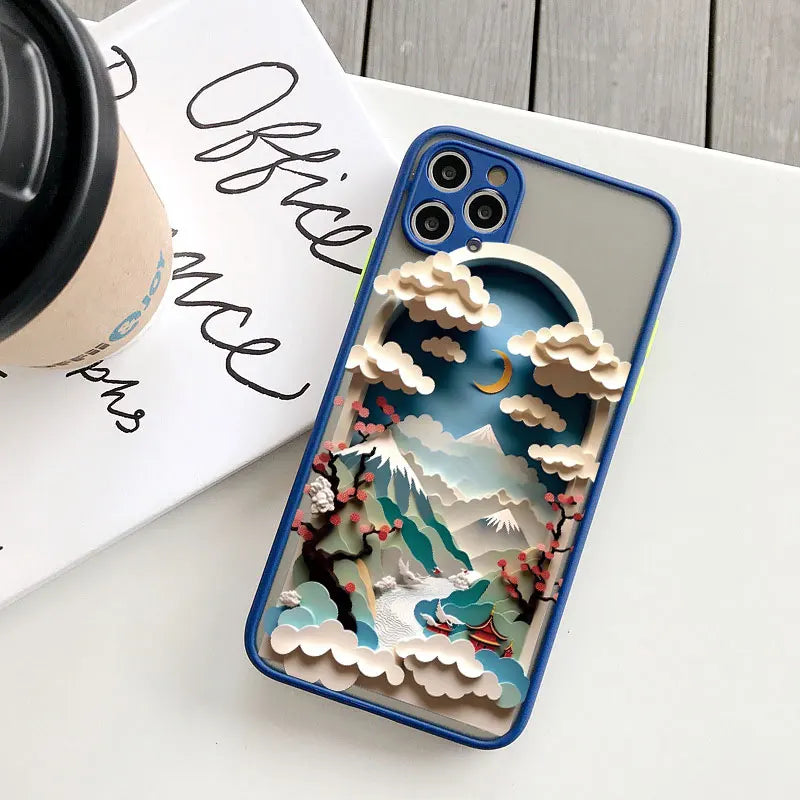 Phone case with a mountain and cloud design on a white surface with a coffee cup and book.