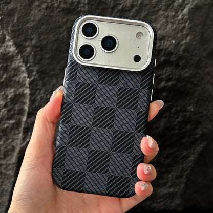 Hand holding a phone case with a checkered pattern against a dark background