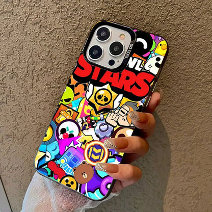 A hand holding a phone case decorated with a colorful, busy cartoon sticker collage and the word 'STARS' in red. The hand has long nude manicured nails with clear rhinestones, and the background is a textured beige wall.