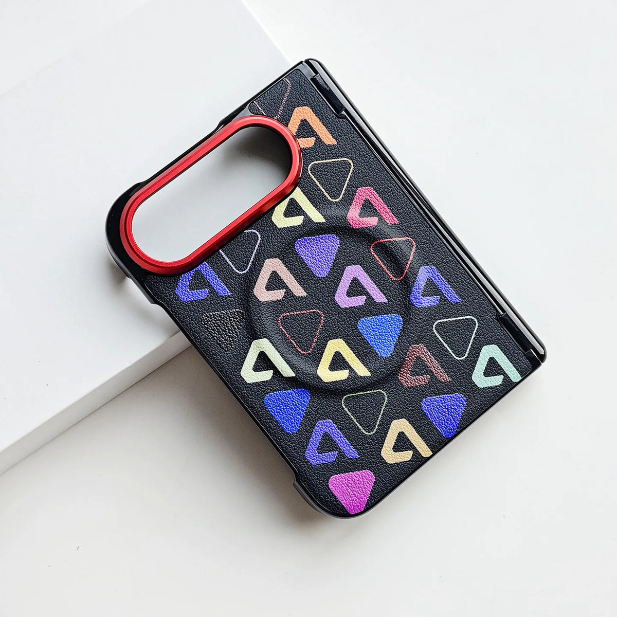 A black textured phone case with a colorful geometric triangle pattern and a red camera bumper, shown on a clean white background.