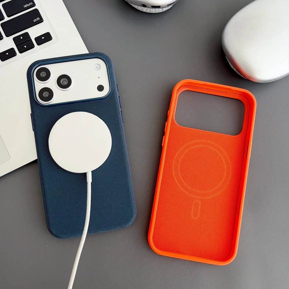 Two phone cases, one blue and one orange, on a gray surface with a laptop in the background.