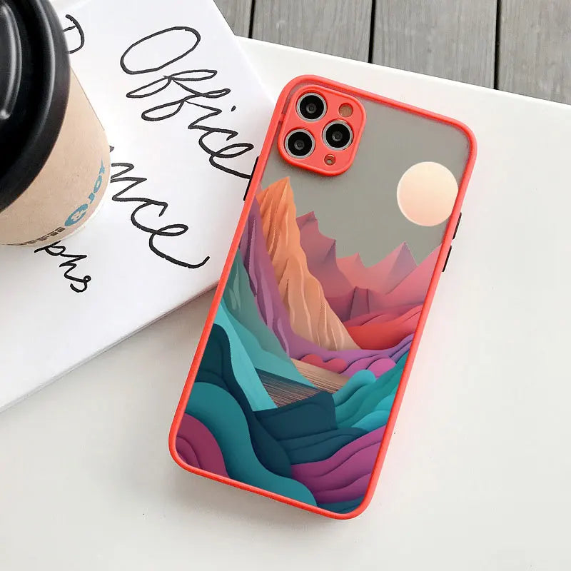 Phone case with colorful mountain design on a white surface with a coffee cup and text.