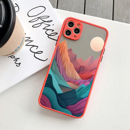 Phone case with colorful mountain design on a white surface with a coffee cup and text.