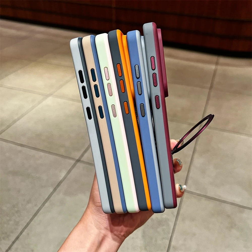 A hand holds a vertical stack of colorful phone cases with matching wrist loops, shown against a tiled indoor floor.