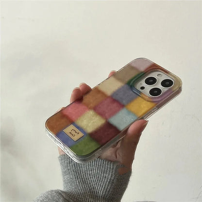 Phone case with colorful square pattern held by a person against a plain background
