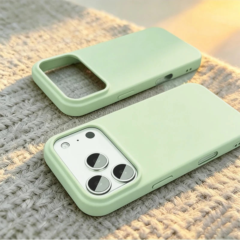 Two light mint green phone cases shown on a textured beige knit surface, one fitted on a phone and one empty, with warm sunlight casting soft shadows.