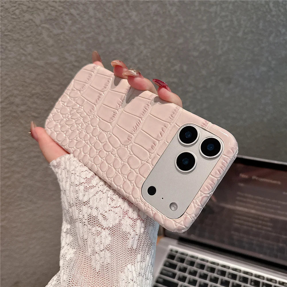 Phone case with crocodile texture held by a hand, with a laptop in the background.
