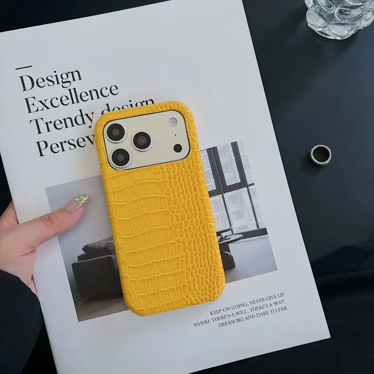 Yellow textured phone case on a magazine with text and a ring in the background