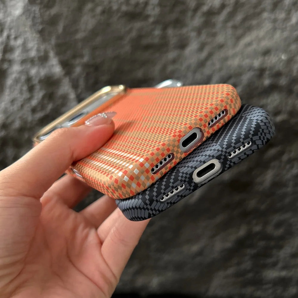 Two phone cases, one orange and one black, held by a hand against a dark background.