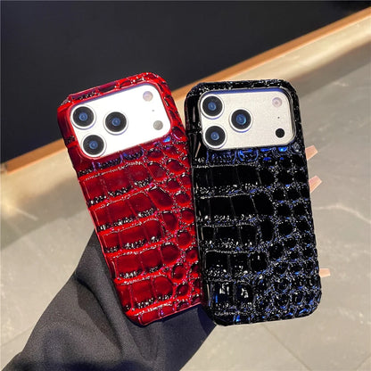 Two phone cases, one red and one black, with crocodile texture on a neutral background.