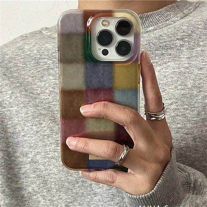 Hand holding a phone with a colorful case against a neutral background