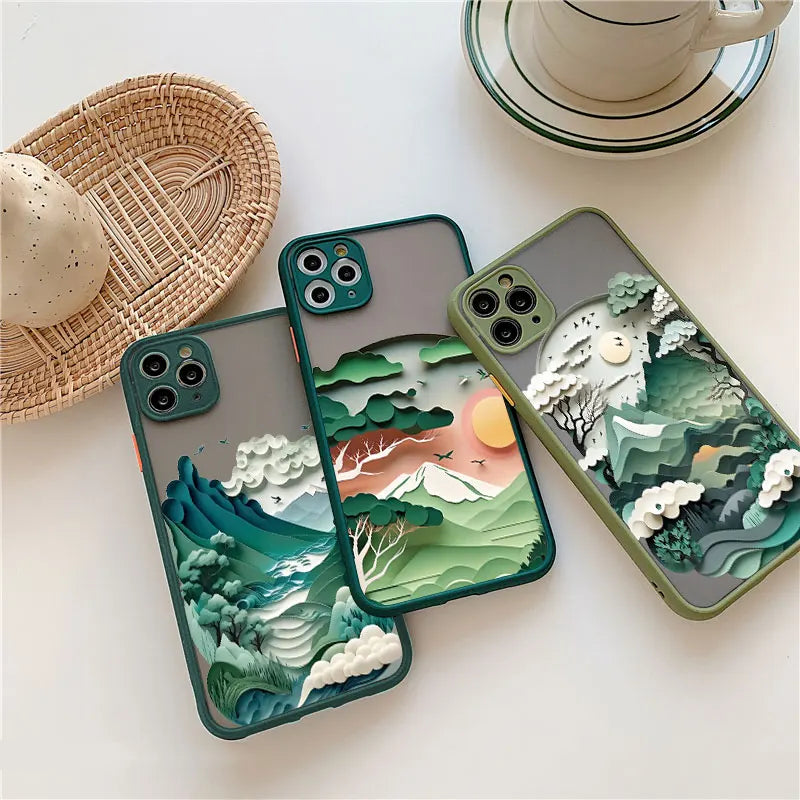 Three phone cases with 3D landscape designs on a white surface with a cup and saucer.