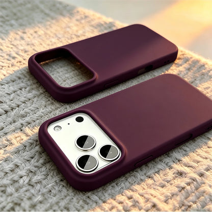 Two dark purple phone cases shown on white iPhones, resting on a textured beige knit blanket with warm sunset light.