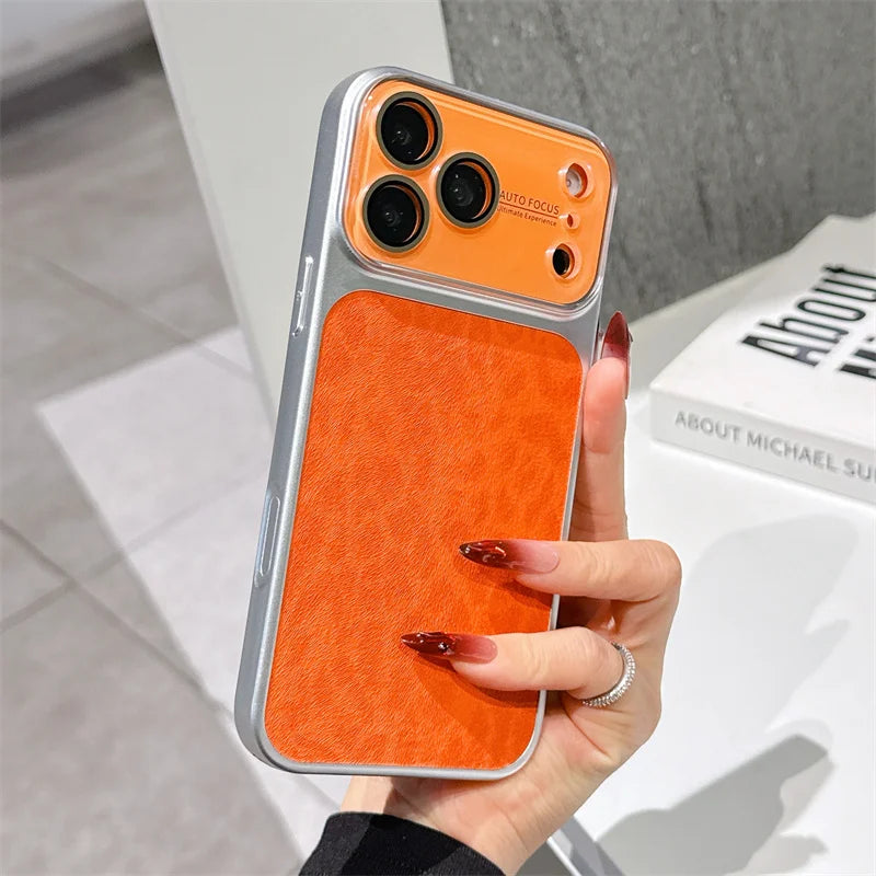 A hand with long red manicured nails holds a smartphone case featuring a bright orange textured back panel and a silver metallic bumper frame. The case has a clear camera cutout area with orange accents.