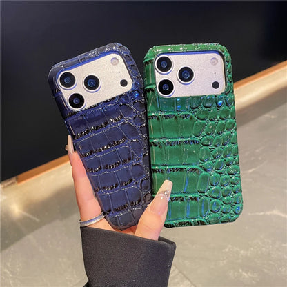 Two phone cases, one blue and one green, held by a hand against a dark background.