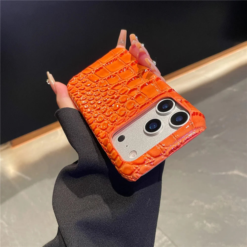 Orange crocodile texture phone case held by a hand against a neutral background