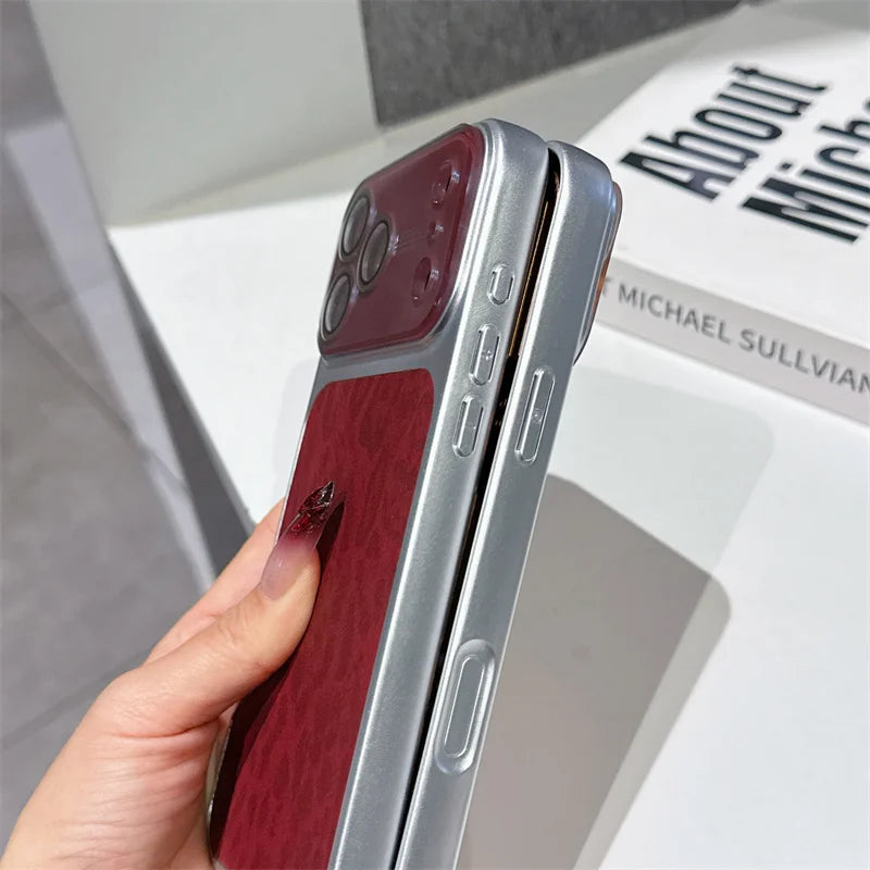 A hand holds a slim smartphone case shown from the side, featuring a deep burgundy wood-grain back panel and a metallic silver frame. The phone inside is partially visible.