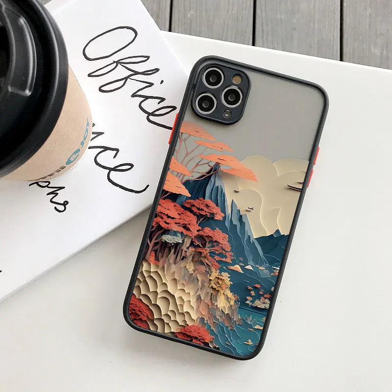Phone case with a mountain and cloud design on a white surface with a coffee cup and book.