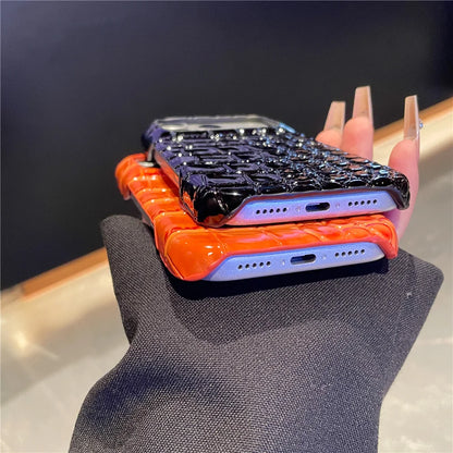 Two phone cases, one black and one orange, on a textured surface with a blurred background.