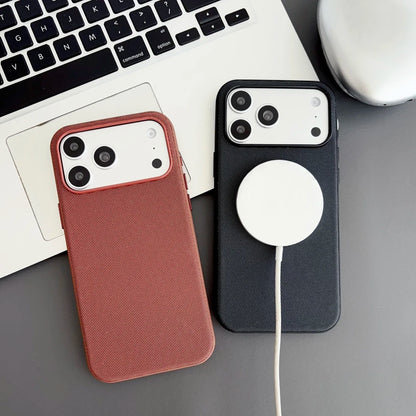 Two phone cases, one brown and one black with a MagSafe disc, on a desk with a laptop.