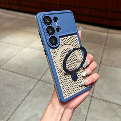 A hand holding a blue and beige phone case with a black magnetic ring stand, photographed in a real indoor environment with tiled flooring.