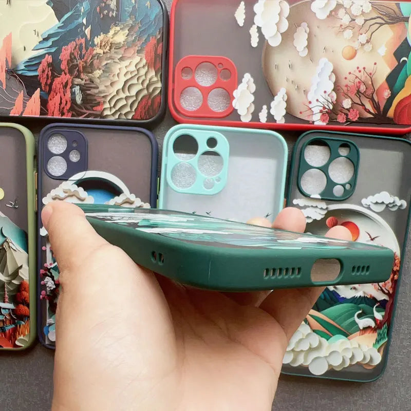 Hand holding a phone with colorful phone cases displayed around it
